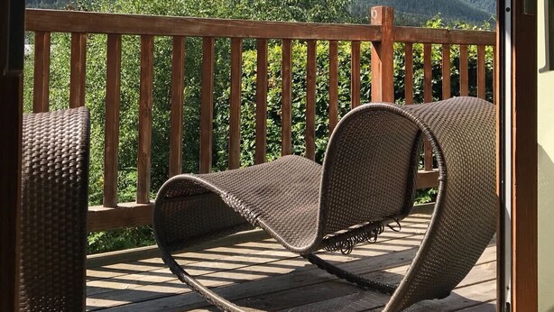 A balcony with wicker chairs, a wooden deck, and a mountain view. - Popular, Stylish Chalet. Exceptional location with stunning Mont Blanc views. (Chamonix-Mont-Blanc)