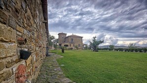 A stone building with a tower, surrounded by a grassy lawn and trees. - Relax, wellness, italian elegance (Castellabate)
