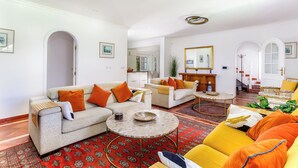 A spacious living room with a sofa, armchairs, a coffee table, and a patterned rug.