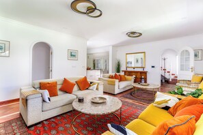 Ein geräumiges Wohnzimmer mit einer Couch, Sesseln, einem Couchtisch und einem gemusterten Teppich.