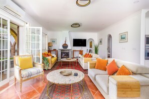 Ein Wohnzimmer mit Kamin, Fernseher und einer Couch mit orangenen Kissen.