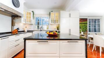 A modern kitchen with white cabinetry, a black countertop, and a bowl of fruit.