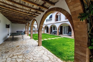 Un patio con mesa de ping pong, suelo de piedra y columnas de ladrillo abovedadas.