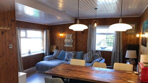 A cozy cabin interior with a wooden interior, a sofa set, a dining table, and pendant lights. - Detached Cottage In Heart Of This Beautiful Harbour Village (Seahouses)