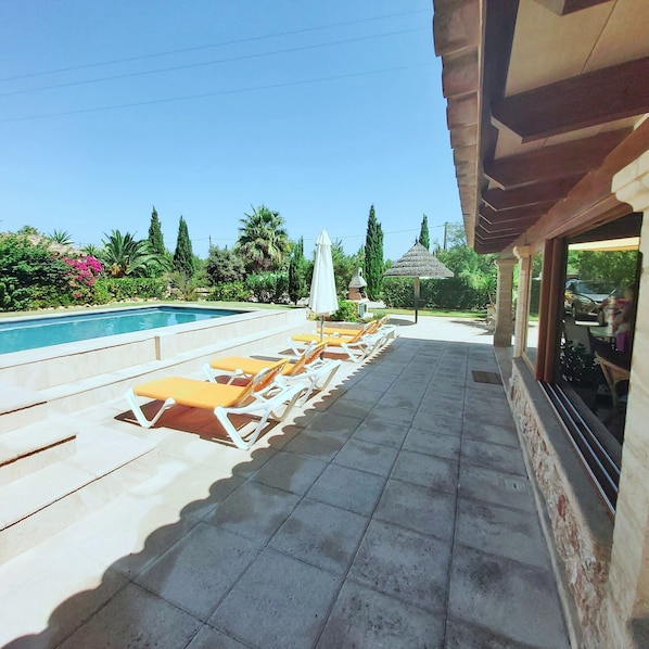 A pool area with lounge chairs and a pergola.