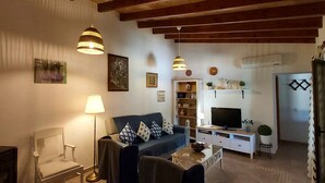 Un salon avec un canapé, des fauteuils, un téléviseur et une bibliothèque.