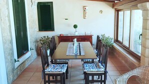 Un coin repas avec une table et des chaises en bois, une plante en pot et une vue dégagée grâce à de grandes fenêtres.