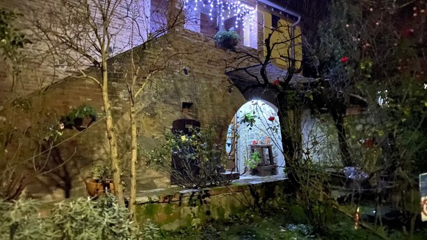 Een stenen gebouw met een klein balkon, een houten deur en een raam versierd met lichtjes.