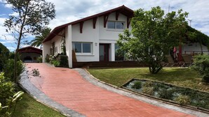 Una casa de dos pisos con techo rojo, un porche delantero y un camino de entrada pavimentado.