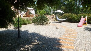 A garden with a wooden pathway, a hammock, a slide, and a tent. - Casa Niperu in the countryside a few meters from the beaches of Cala Ginepro (Cala Liberotto)