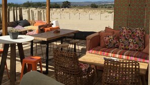 Un espacio al aire libre con una mesa y sillas, un sofá y un toldo sombreado.
