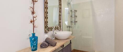 A bathroom with a sink, mirror, and shower.