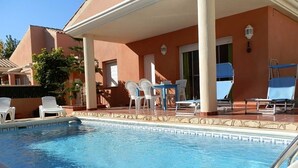 A swimming pool with lounge chairs and a covered patio area. - CASA JERONI, Ideal house for your holidays near the sea, free wifi, optional air conditioning, private pool, pets allowed, dog’s beach (Deltebre)