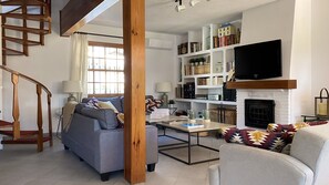 A living room with a grey sofa, a coffee table, a fireplace, and a bookshelf filled with books and decorative items.