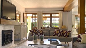 A living room with a fireplace, a sofa with patterned cushions, a coffee table, and a television mounted on the wall. - Chalet in Puerto Marina, Benalmadena Costa. (Benalmádena)