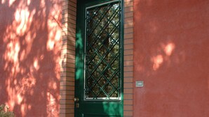 A green door with a window, a potted plant, and a tiled floor.