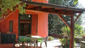 A covered patio with a table and chairs, a door, and a window.