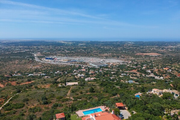 An aerial view of a coastal town with a prominent road, residential areas, and a large body of water.