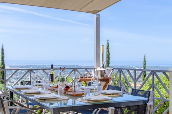 An outdoor dining area with a table set for two, overlooking a scenic view.