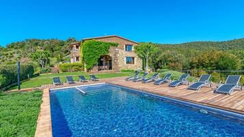 Relax by the serene pool surrounded by lush greenery and hills.