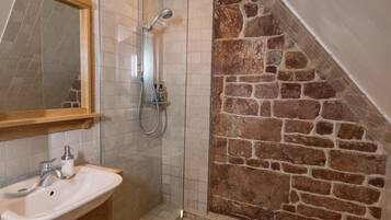 A bathroom with a shower, a sink, and a mirror.