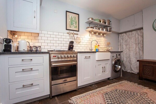 A compact kitchen with white cabinets, a built-in oven, a washing machine, and a tiled backsplash. - Gorgeous, Georgian Townhouse- Central Bath (PP) (Bath)