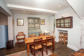 A dining area with a wooden table and chairs, a cabinet with glass doors, and a radiator.