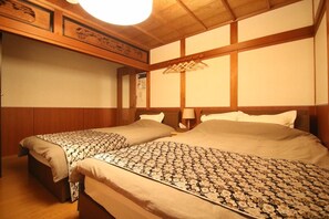 Ein Hotelzimmer mit zwei Betten, Holz-Kopfteilen, einem Kleiderhaken und einer Deckenleuchte.