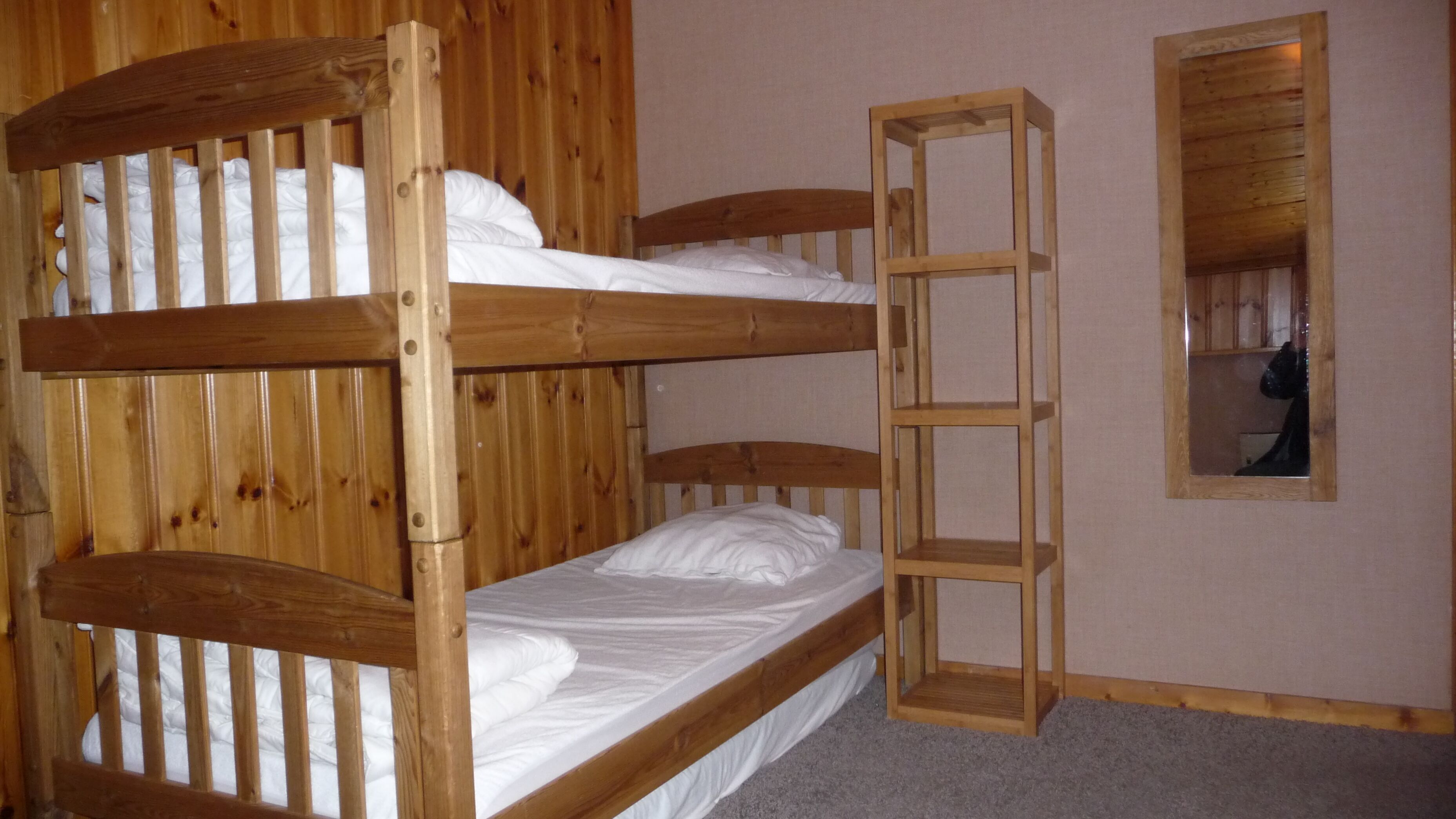 Een stapelbed met een houten frame en witte beddengoed.