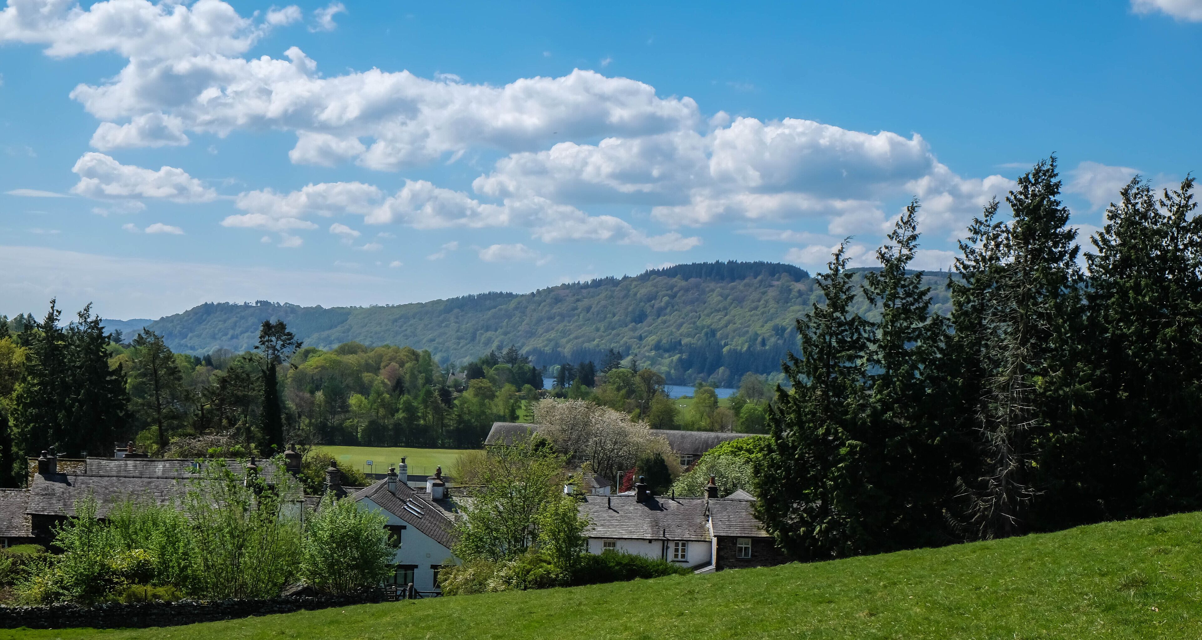 A rural landscape with houses, green fields, and a hill in the background.