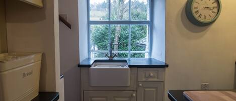 A kitchen with a window, a sink, and a clock on the wall.