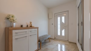 A hallway with a white cabinet, a bench, and a door leading to another room.