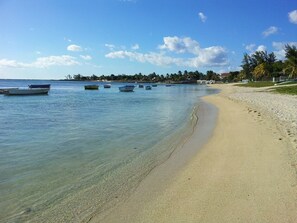 A beach with clear water and several boats.