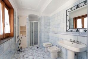 A bathroom with a shower, toilet, bidet, and sink, featuring blue tiles and a wooden window frame. - Villa Ciuffo with private pool (Massa Lubrense)