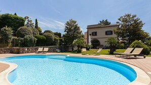 A swimming pool with lounge chairs and a stone wall. - Villa Ciuffo with private pool (Massa Lubrense)