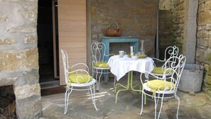 Un espace extérieur aménagé avec des murs en pierre, comprenant une table et quatre chaises.