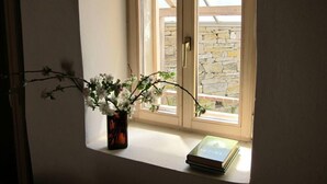 Une fenêtre avec un vase de fleurs et un livre posé sur le rebord.