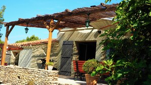 A stone-walled patio with a pergola, potted plants, and outdoor furniture. - A cozy home surrounded by nature, with a private pool and tennis court (Cabrières-D'avignon)