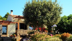 A stone house with a tiled roof, surrounded by a garden with various plants and flowers. - A cozy home surrounded by nature, with a private pool and tennis court (Cabrières-D'avignon)