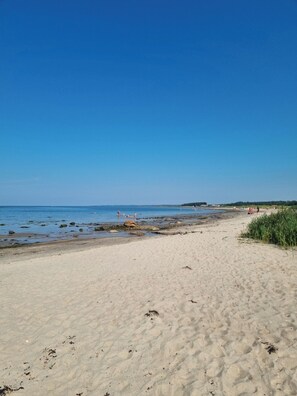 A sandy beach with clear blue water, some rocks, and a few people in the distance. - Cozy vacation home for 5 people in Hallandsåsen. (Hjärnarp)
