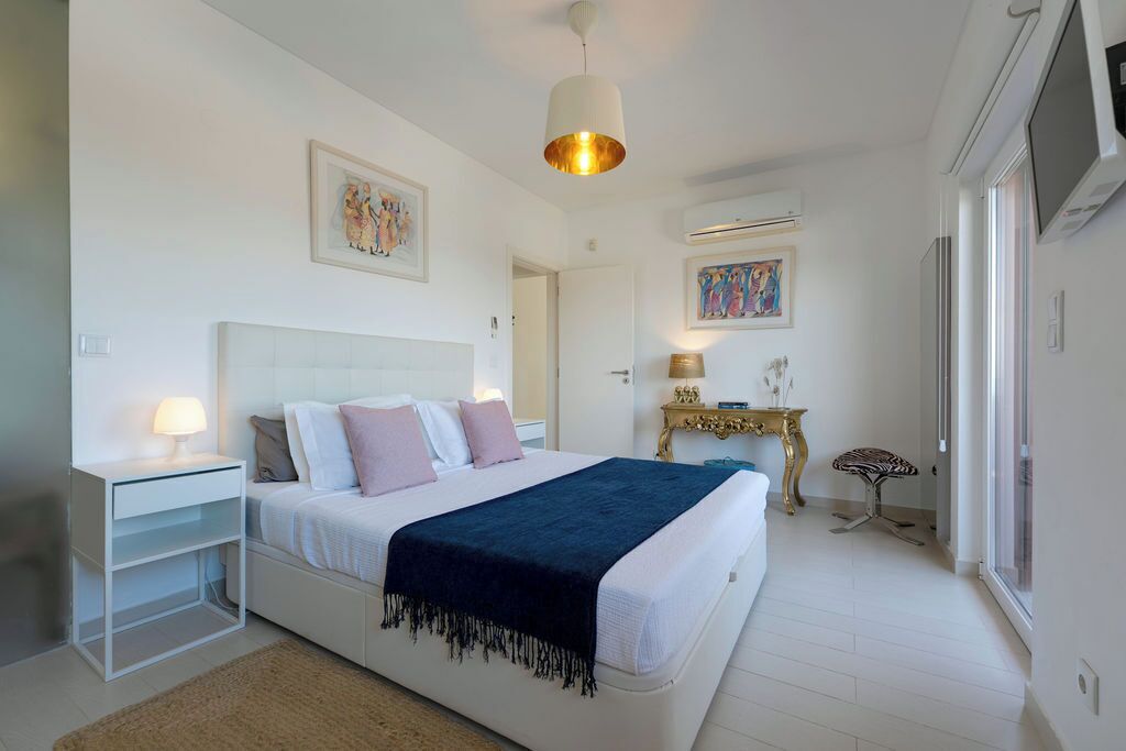 A bedroom with a bed, bedside tables, a lamp, a decorative table, and artwork on the walls.
