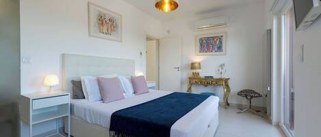 A bedroom with a bed, bedside tables, a lamp, a decorative table, and artwork on the walls.