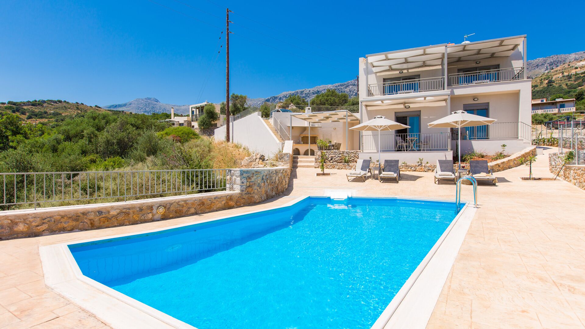 Un bâtiment moderne à deux étages doté d’une piscine, d’un espace extérieur aménagé et offrant une vue sur le paysage environnant.