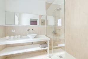 Een bad/douchecombinatie, een haardroger, handdoeken, toiletpapier