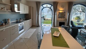 Una cocina moderna con comedor, ventanas amplias e iluminación colgante.