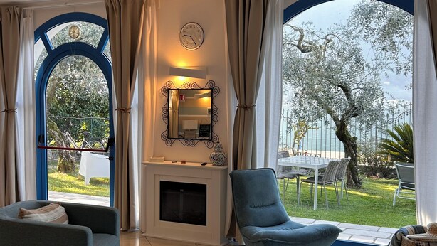 Una sala de estar con chimenea, un sofá, una silla y una mesa de centro de vidrio.