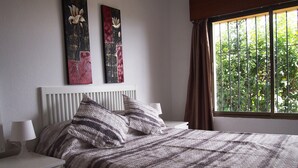 A bedroom with a bed, nightstands, a window with curtains, and two wall-mounted artworks. - Enchanting villa with private pool and stunning views, close to beach. (Benalmadena)
