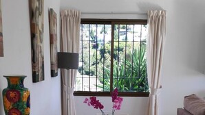 A dining area with a table, chairs, a vase with flowers, and a window with curtains. - Enchanting villa with private pool and stunning views, close to beach. (Benalmadena)