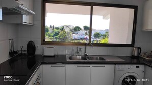 A compact kitchen with a window view, a washing machine, and a toaster. - Enchanting villa with private pool and stunning views, close to beach. (Benalmadena)
