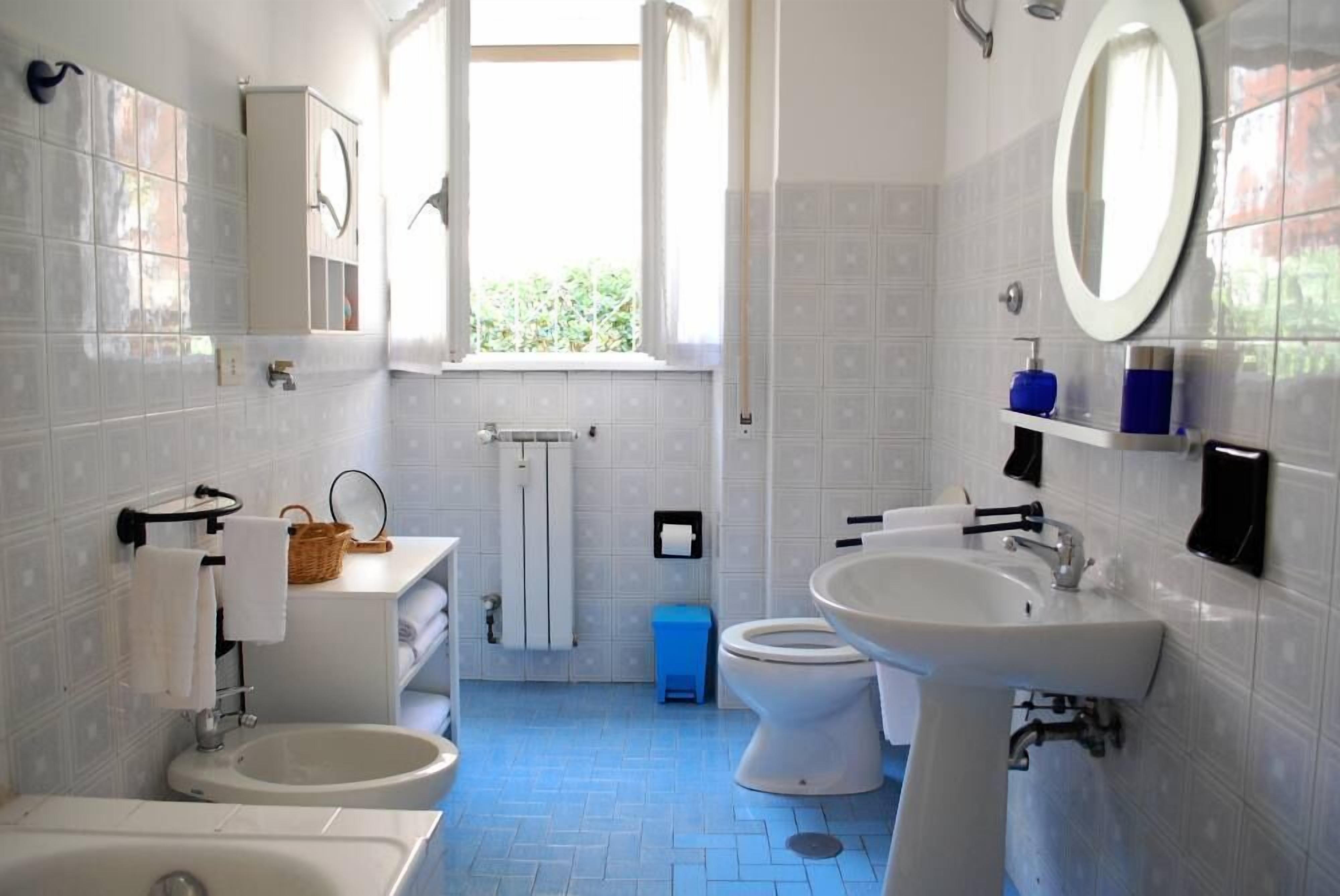 A bathroom with a bathtub, two sinks, a toilet, and a window.